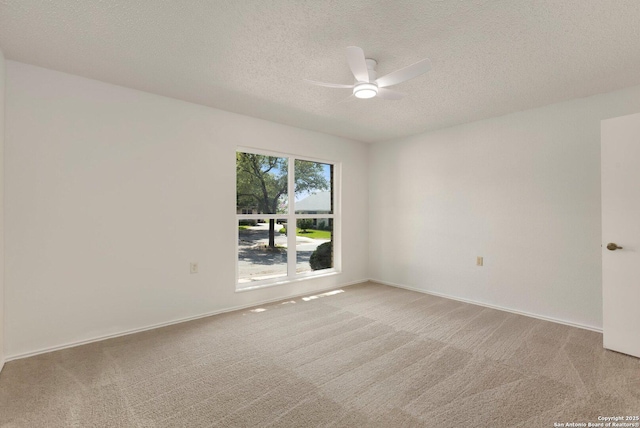 spare room featuring ceiling fan, light colored carpet, a textured ceiling, and baseboards