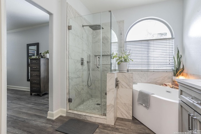 full bathroom featuring a stall shower, a bath, vanity, ornamental molding, and wood finished floors