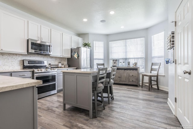 kitchen featuring stainless steel appliances, tasteful backsplash, healthy amount of natural light, light countertops, and recessed lighting