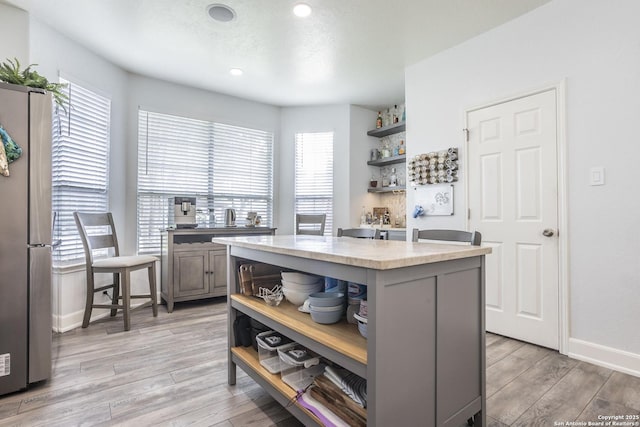 kitchen with open shelves, freestanding refrigerator, light countertops, plenty of natural light, and recessed lighting