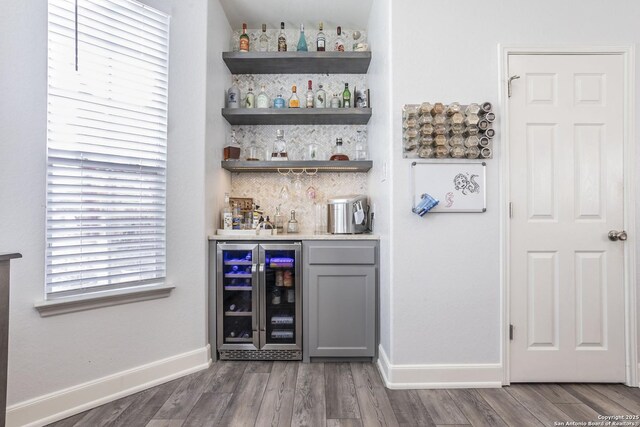 indoor wet bar with beverage cooler, tasteful backsplash, wood finished floors, and baseboards
