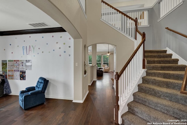 foyer with stairway, baseboards, visible vents, arched walkways, and hardwood / wood-style floors