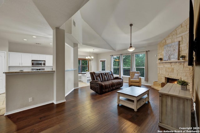 living room with lofted ceiling, baseboards, an inviting chandelier, visible vents, and dark wood-style floors