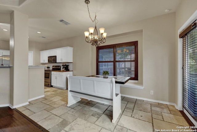 dining area with stone tile floors, a healthy amount of sunlight, an inviting chandelier, and visible vents