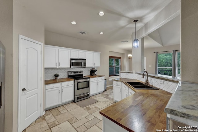 kitchen featuring a sink, butcher block countertops, backsplash, and appliances with stainless steel finishes