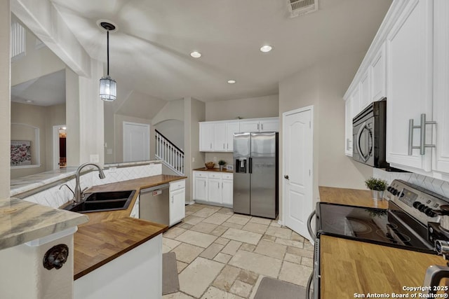 kitchen with visible vents, a sink, wood counters, tasteful backsplash, and appliances with stainless steel finishes