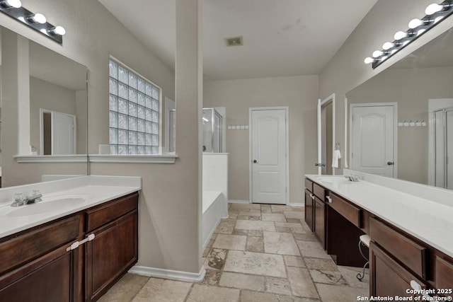bathroom with baseboards, a stall shower, a sink, and stone tile flooring