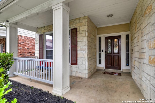 view of exterior entry with covered porch and brick siding