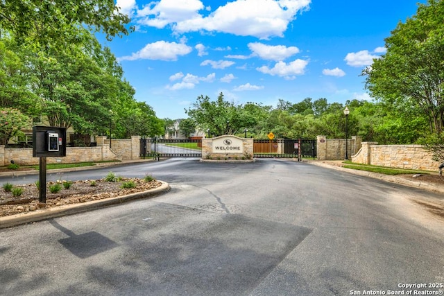 view of street featuring curbs, street lights, a gated entry, and a gate