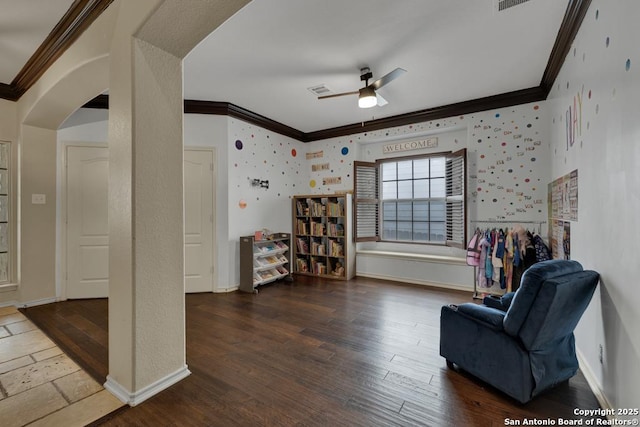 sitting room featuring ornamental molding, arched walkways, and a ceiling fan