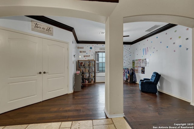 foyer entrance with wood finished floors, ornamental molding, visible vents, arched walkways, and baseboards