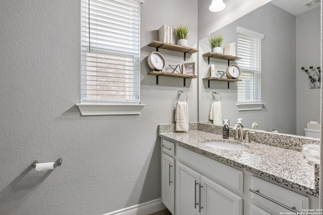 bathroom featuring vanity, visible vents, and a textured wall