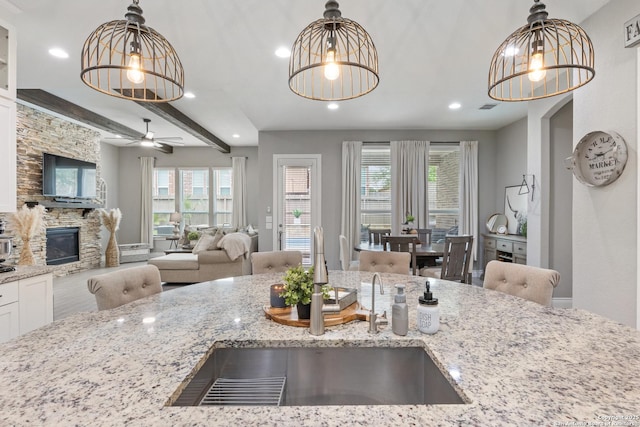 kitchen with light stone countertops, pendant lighting, recessed lighting, a sink, and open floor plan