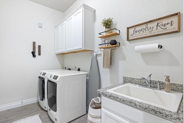 laundry area with a sink, cabinet space, light wood-type flooring, washer and dryer, and baseboards