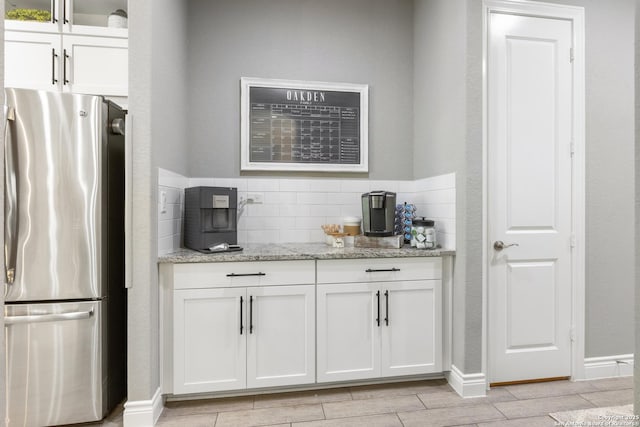 bar with freestanding refrigerator, baseboards, wood tiled floor, and backsplash