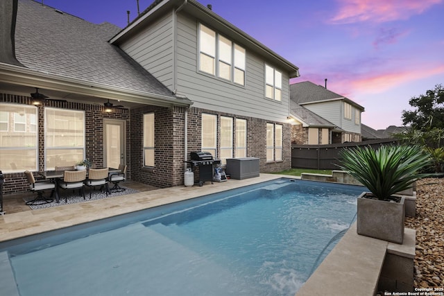 pool at dusk featuring an outdoor hangout area, a patio, a fenced in pool, and grilling area