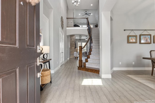 entryway featuring stairs, wood finished floors, arched walkways, a ceiling fan, and baseboards
