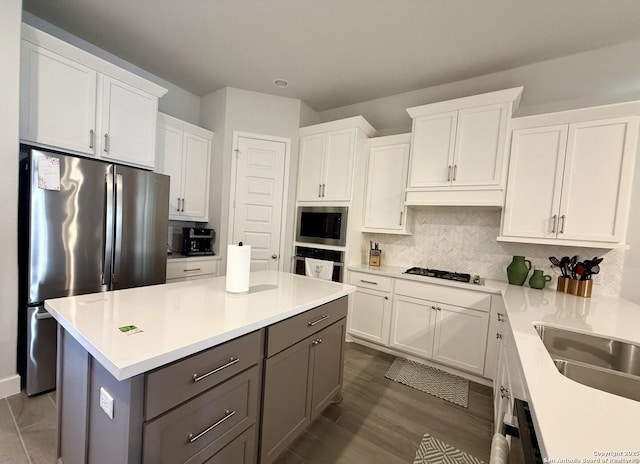 kitchen featuring light countertops, a sink, white cabinets, gray cabinetry, and appliances with stainless steel finishes
