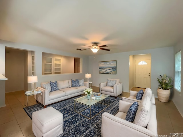 tiled living area featuring built in shelves and a ceiling fan