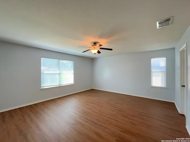 empty room with ceiling fan, baseboards, visible vents, and wood finished floors