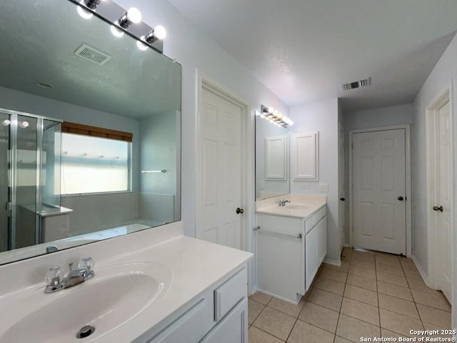 bathroom featuring tile patterned floors, visible vents, a shower stall, and a sink