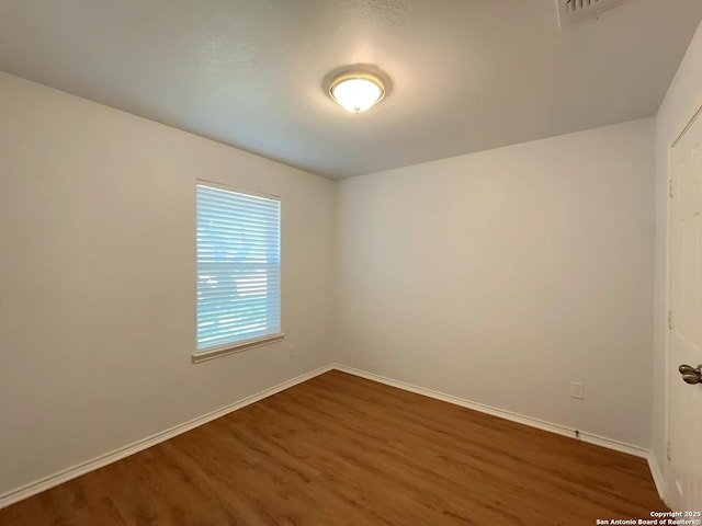 spare room with wood finished floors and baseboards