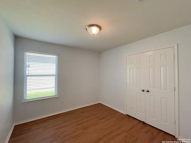 unfurnished bedroom with baseboards, a closet, and wood finished floors