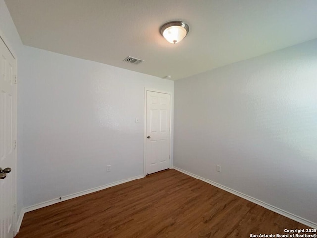unfurnished room with baseboards, visible vents, and wood finished floors