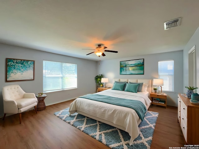 bedroom featuring baseboards, visible vents, a ceiling fan, and wood finished floors