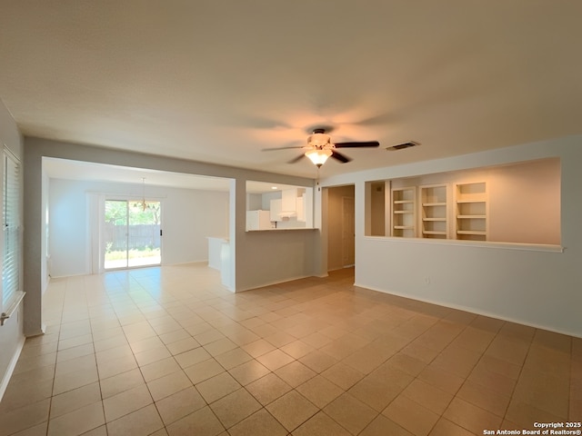 spare room featuring baseboards, ceiling fan, visible vents, light tile patterned flooring, and built in shelves
