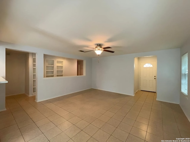 spare room with built in features, baseboards, light tile patterned flooring, and ceiling fan