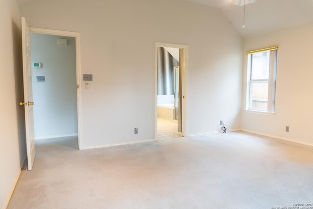 empty room with vaulted ceiling, light carpet, baseboards, and a ceiling fan