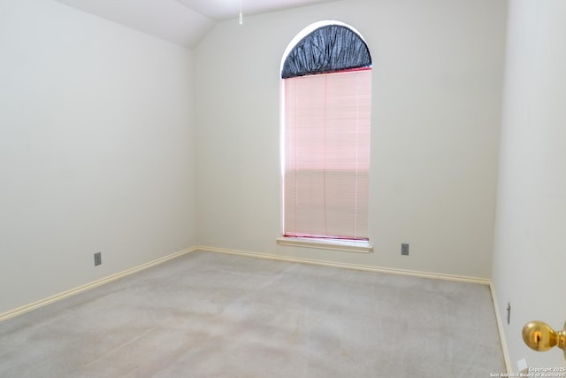 carpeted empty room with baseboards and vaulted ceiling