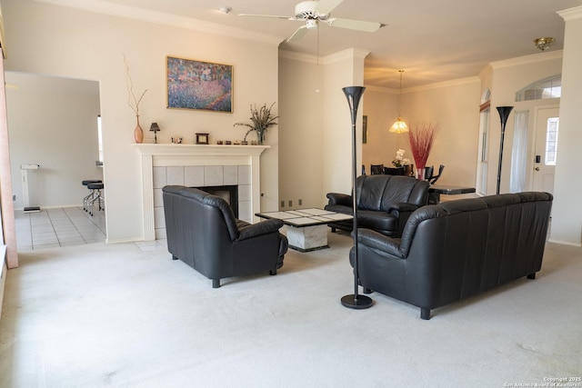 living area with ornamental molding, a tiled fireplace, ceiling fan, and carpet