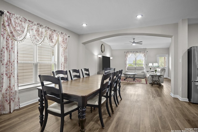 dining space with arched walkways, baseboards, ceiling fan, and wood finished floors