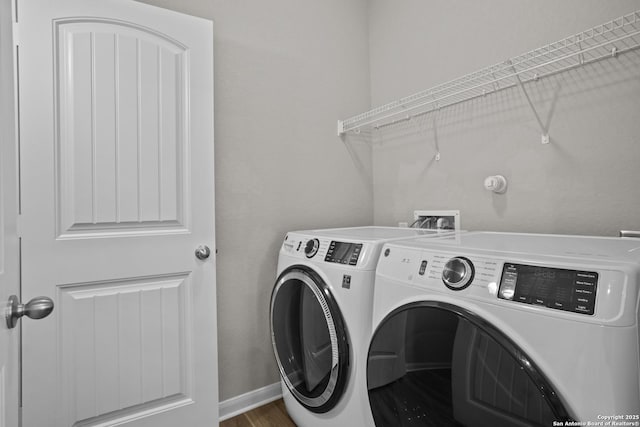 clothes washing area featuring separate washer and dryer, laundry area, baseboards, and wood finished floors
