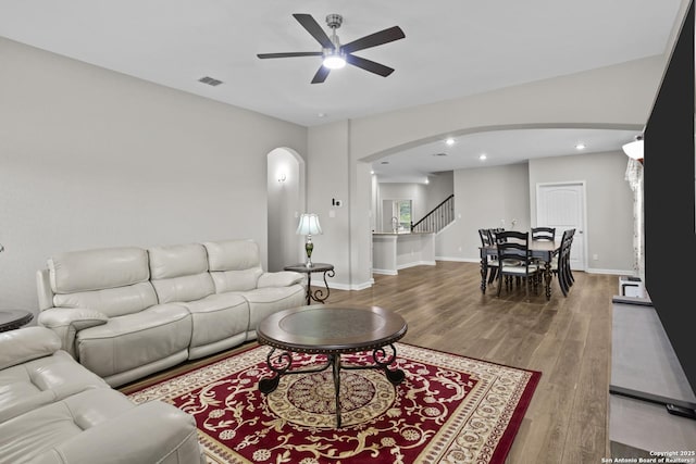 living area with arched walkways, ceiling fan, visible vents, and wood finished floors