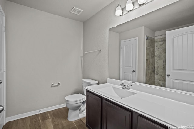 full bathroom with toilet, wood finished floors, vanity, visible vents, and baseboards