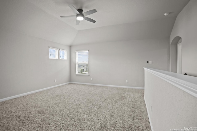 empty room featuring carpet flooring, baseboards, lofted ceiling, and a ceiling fan