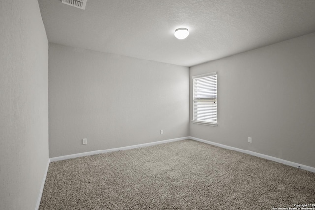 carpeted spare room with baseboards, visible vents, and a textured ceiling