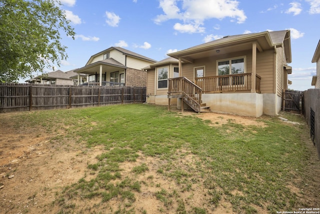 rear view of house featuring a yard and a fenced backyard