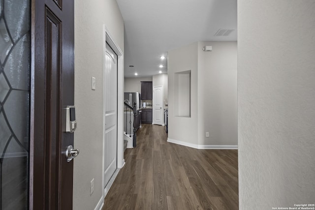 hallway featuring baseboards, dark wood-style floors, and visible vents