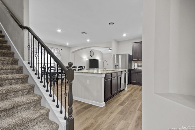 kitchen with light wood-type flooring, visible vents, arched walkways, appliances with stainless steel finishes, and light stone counters