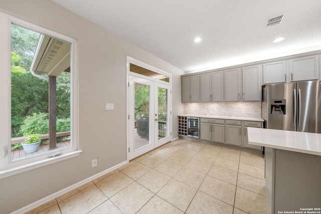 kitchen featuring beverage cooler, stainless steel fridge with ice dispenser, gray cabinets, visible vents, and light countertops