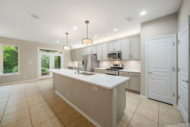 kitchen with an island with sink, a sink, visible vents, appliances with stainless steel finishes, and light tile patterned flooring