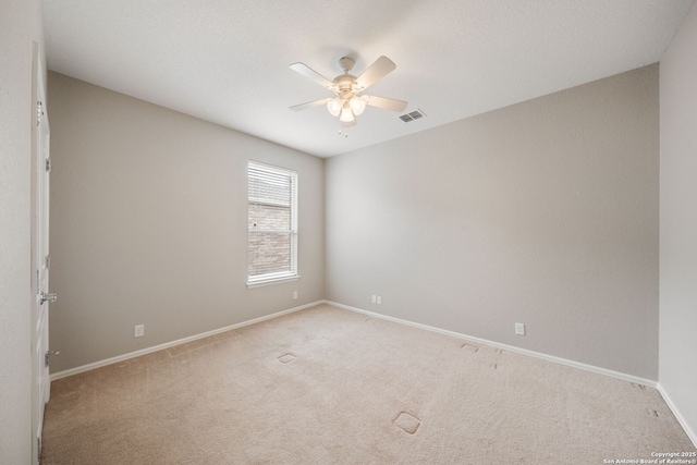 spare room with visible vents, baseboards, a ceiling fan, and light carpet