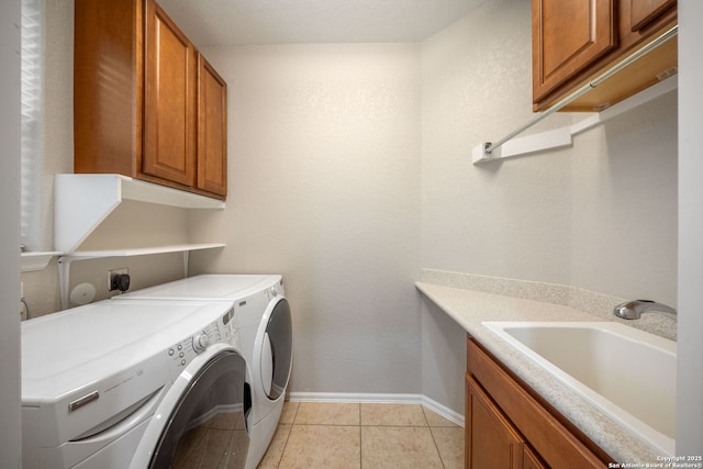 laundry room featuring light tile patterned floors, a sink, cabinet space, washer and clothes dryer, and baseboards