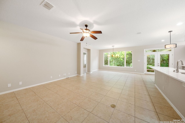 empty room featuring french doors, visible vents, a ceiling fan, light tile patterned floors, and baseboards