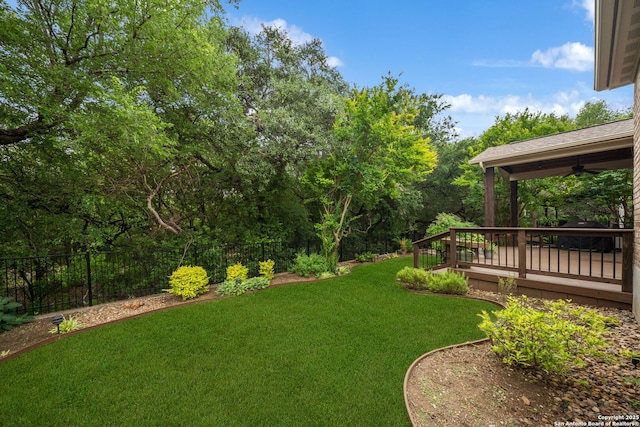 view of yard featuring fence, a wooden deck, and ceiling fan