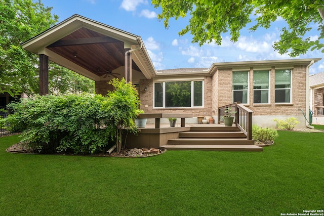 back of house featuring a lawn, brick siding, a wooden deck, and a ceiling fan